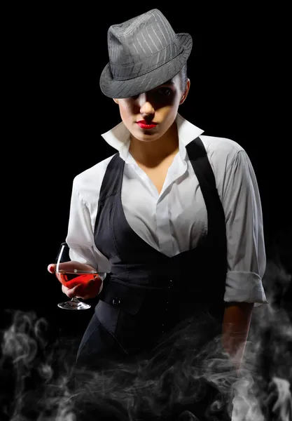 Meisje in manly stijl met brandy glas en rook — Stockfoto