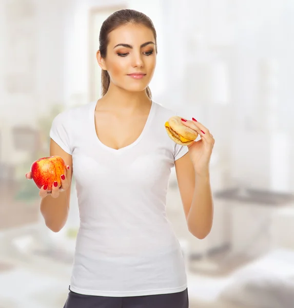 Chica dudando con manzana y hamburguesa —  Fotos de Stock