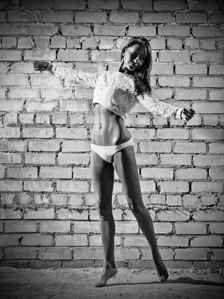 Young dancing woman on brick wall background (monochrome ver) — Stock Photo, Image