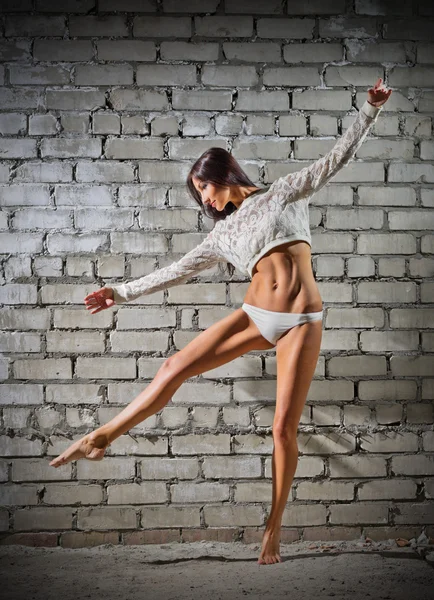 Young dancing woman on brick wall background (normal version) — Stock Photo, Image