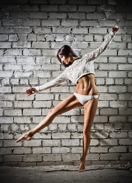 Tuğla duvar arka plan (karanlık sürümü üzerinde dans eden genç kadın) — Stok fotoğraf