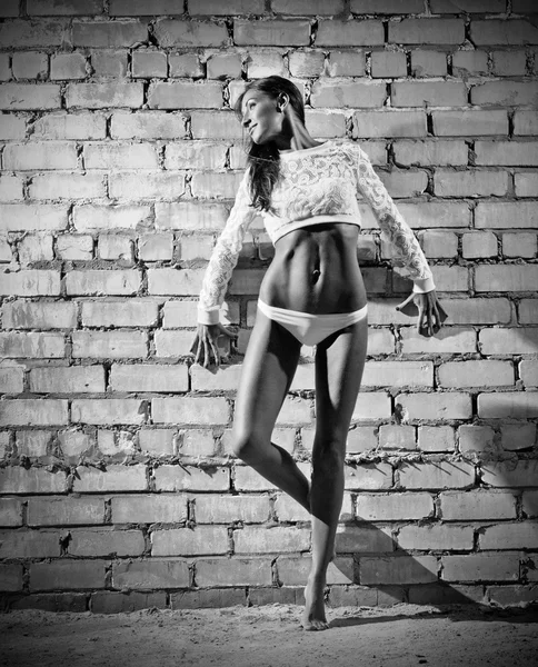 Mujer joven deportiva sobre fondo de pared de ladrillo (versión monocromática ) — Foto de Stock