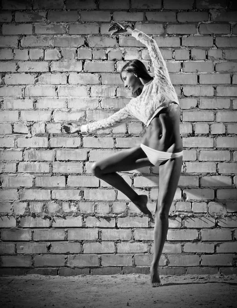 Young dancing woman on brick wall background (monochrome ver) — Stock Photo, Image