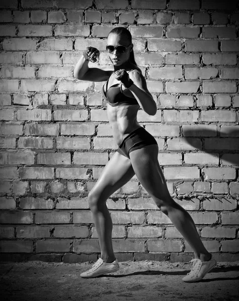 Muscular woman on grey brick wall (monochrome version) — Stock Photo, Image