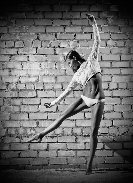 Young dancing woman on brick wall (monochrome version) — Stock Photo, Image