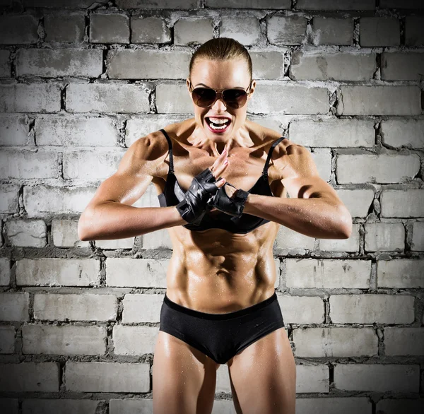 Muscular woman on brick wall (dark version) — Stock Photo, Image