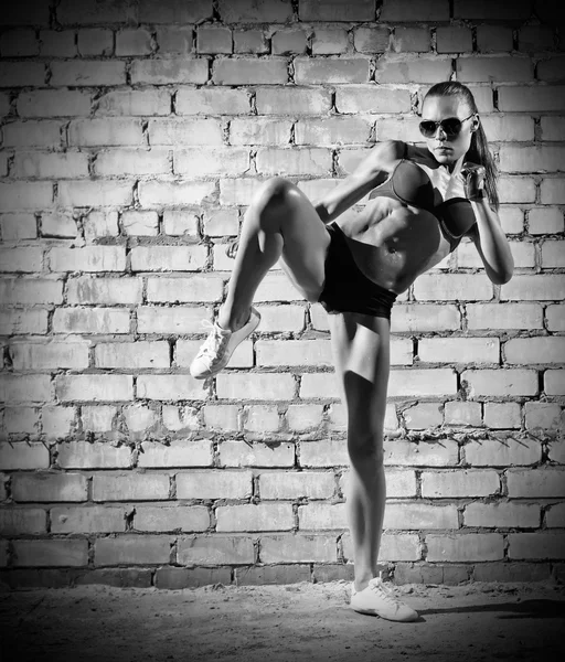 Muscular woman on brick wall (monochrome version) — Stock Photo, Image