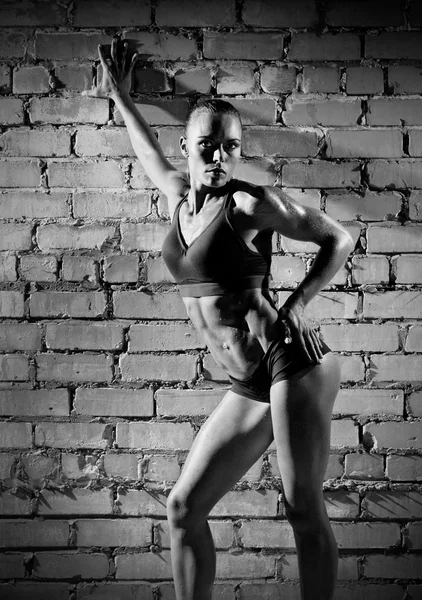 Muscular woman on brick wall (monochrome version) — Stock Photo, Image