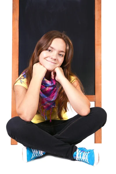 Schoolgirl sitting on floor with blackboard — Stock Photo, Image