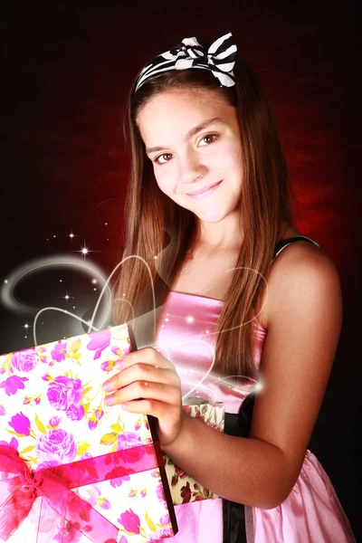 Smiling girl holding present over dark — Stock Photo, Image
