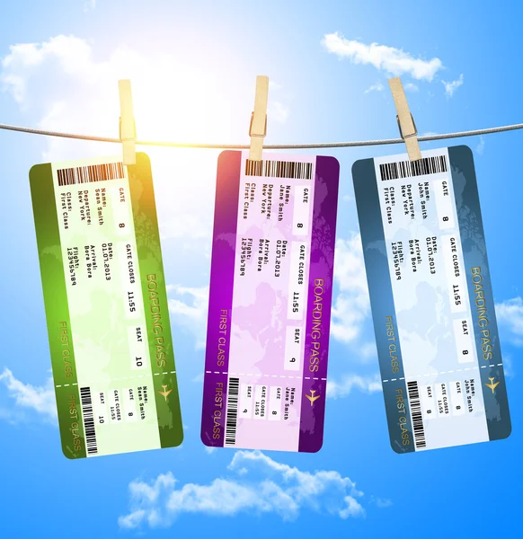 Boarding pass tickets hanging on clothesline over blue sky — Stock Photo, Image