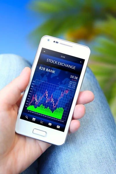 Mobile phone with stock chart holded by hand — Stock Photo, Image