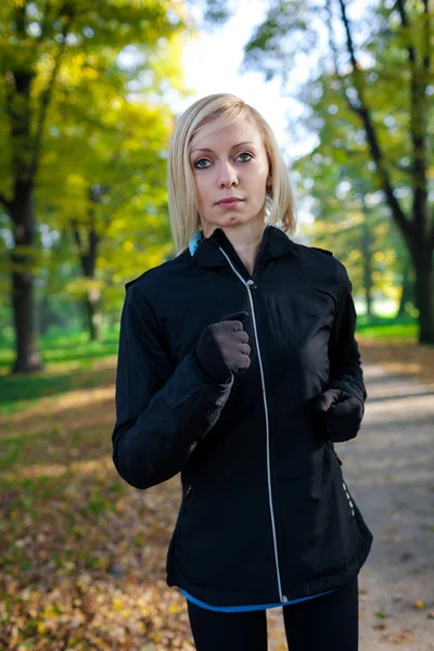 Vrouw loper die in herfst bos loopt Stockfoto