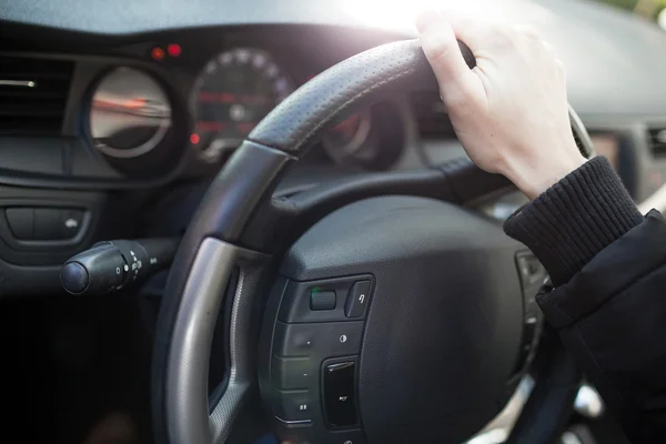 Close-up van een vrouwelijke hand op stuurwiel in een moderne auto Stockfoto