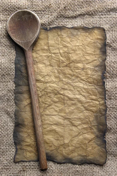 Wooden spoon and old paper on canvas — Stock Photo, Image