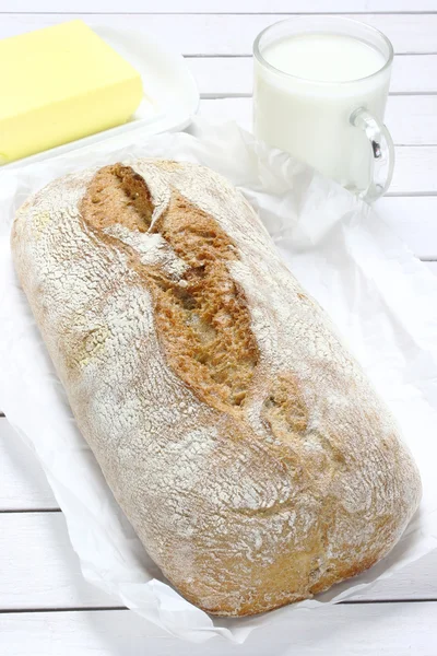 Pão sobre papel e mesa de madeira — Fotografia de Stock