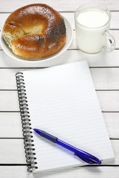 Cuaderno, croissant y leche sobre mesa de madera —  Fotos de Stock