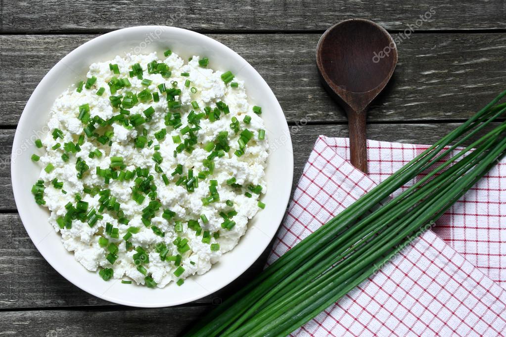 Cottage cheese with chives on wooden table