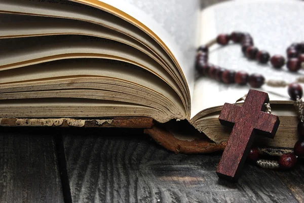 Rosario e libro aperto su tavola di legno — Foto Stock