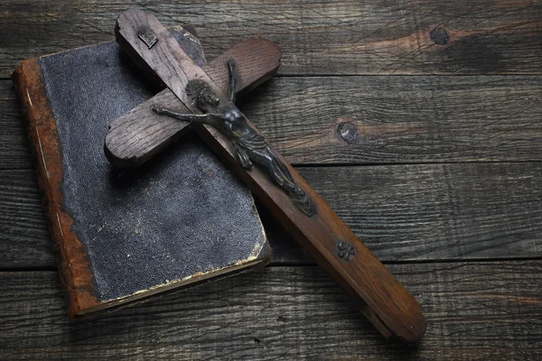 Крест и старая книга на деревянном столе — стоковое фото