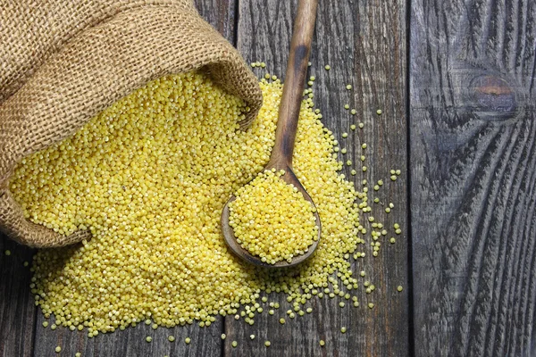 Raw millet on a wooden table — Stock Photo, Image