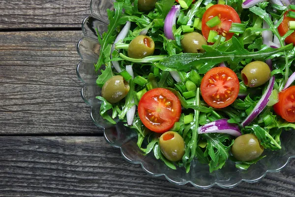 Салат с рукколой, помидорами, луком и зелеными оливками — стоковое фото