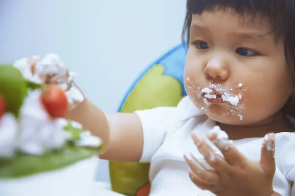 Baby with dirty face and hand eating sweet food