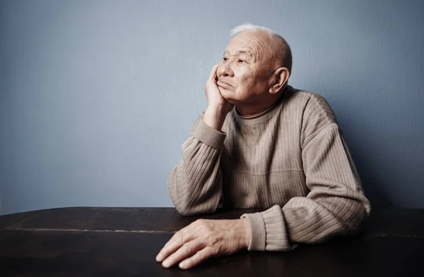 Σκεπτικός Και Συμπονετικός Ηλικιωμένος Που Κάθεται Στο Τραπέζι Εικόνα Αρχείου