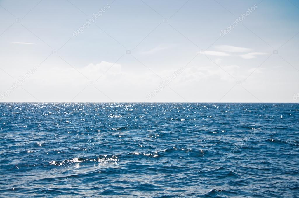 Blue sea with waves and cloudy blue sky
