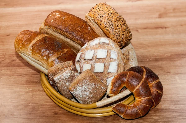 Группа различных типов хлеба на деревянном столе — стоковое фото