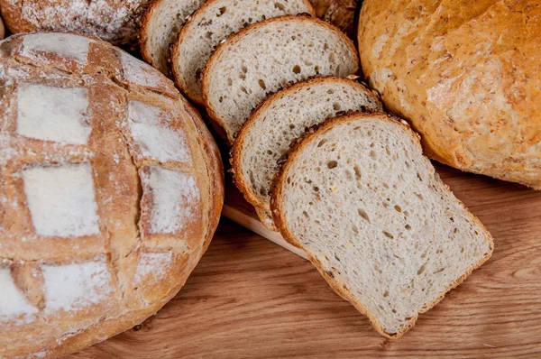 Grupo de diferentes tipos de pan en mesa de madera —  Fotos de Stock