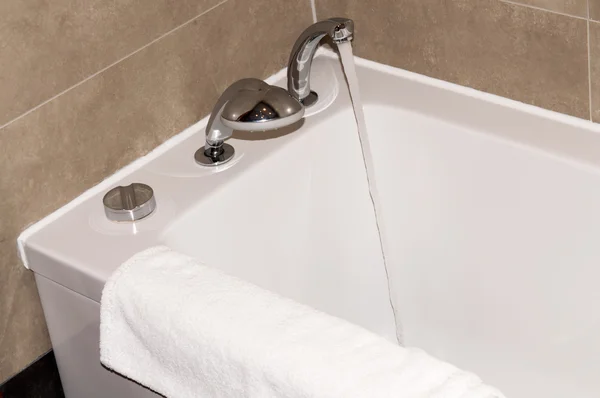 Banheira branca no banheiro com uma toalha — Fotografia de Stock