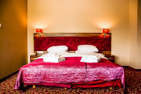 Cama doble en habitación de hotel de lujo con toallas y albornoz —  Fotos de Stock