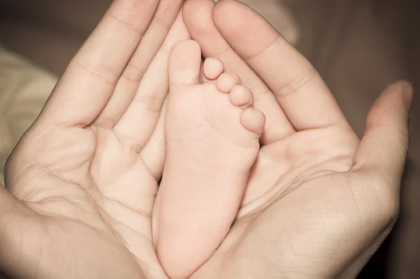 Babyfüße in den Händen der Mutter — Stockfoto