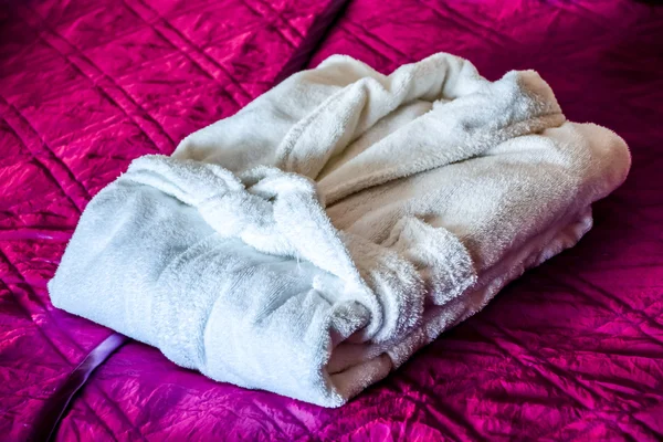 White bathrobe on the bed in hotel room — Stock Photo, Image