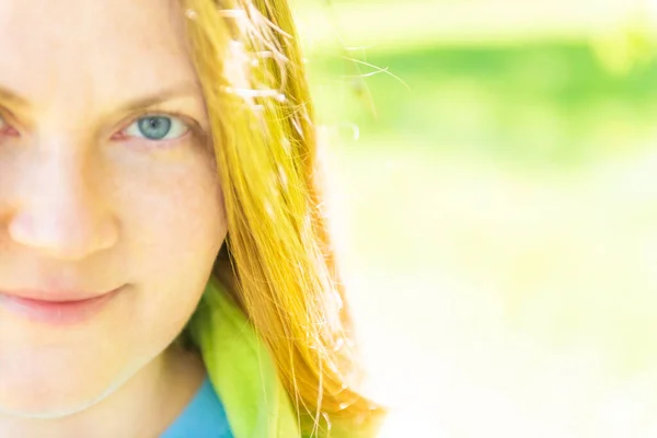 美丽的年轻女子在公园面对着红头发和绿色的阳光背景 — 图库照片