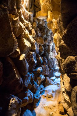 Dark tunnel in stone cave with exit light