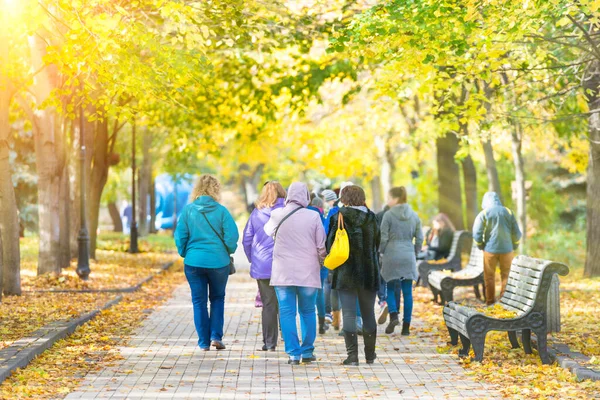 Crowd of people walking in autumn fall city park