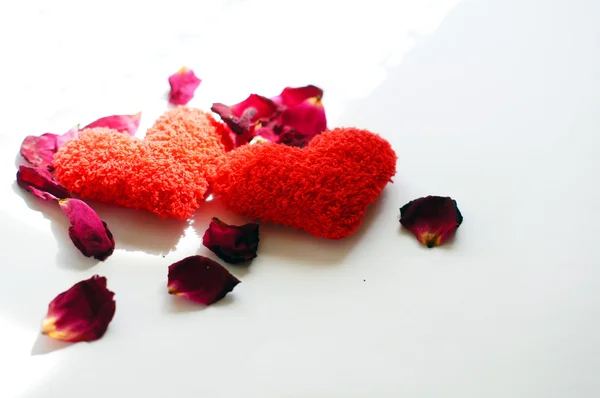 Czerwone serca i płatki róż na białym tle — Zdjęcie stockowe