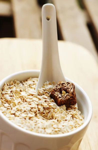Close up of wheat flakes in wooden spoon — Stock Photo, Image
