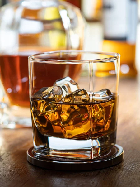 Bicchiere Whisky Sulle Rocce Piano Legno Con Bottiglie Sullo Sfondo — Foto Stock