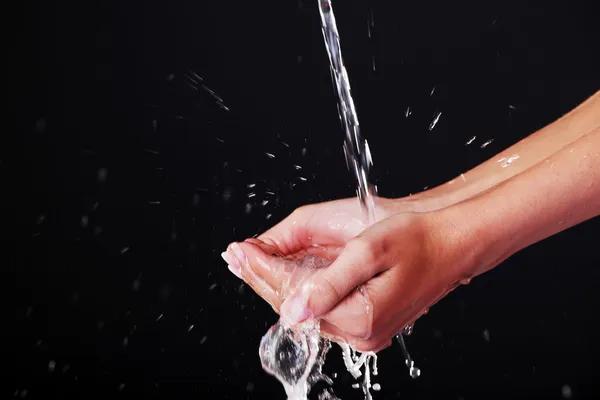 Agua cayendo sobre las manos femeninas — Foto de Stock