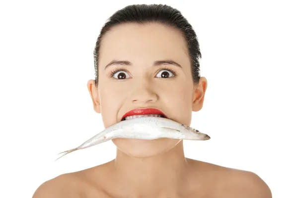 Beautiful young woman with fish in her mouth — Stock Photo, Image