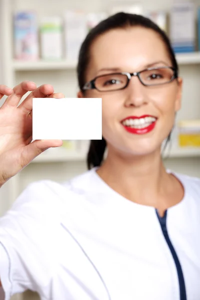 Female pharmacist with business card in pharmacy — Stock Photo, Image