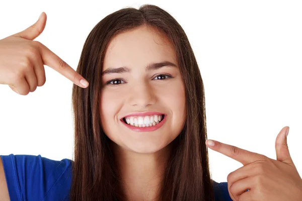 Adolescente menina apontando em seus dentes perfeitos — Fotografia de Stock