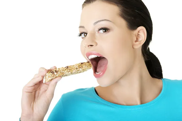 Ung kvinna äta spannmål chokladkaka — Stockfoto