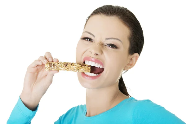 Jovem mulher comendo barra de doces de cereais — Fotografia de Stock