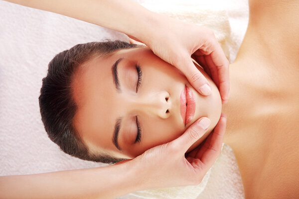 Relaxed woman enjoy receiving face massage