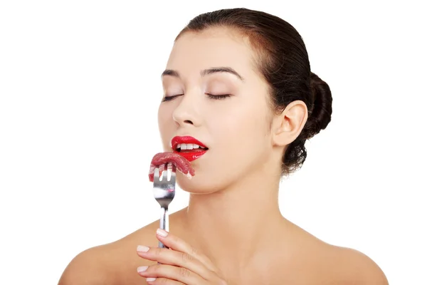 Young beautiful woman eating raw meat. — Stockfoto