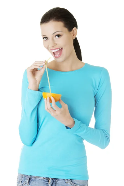 Woman drinking orange juice straight from fruit — Stock Photo, Image